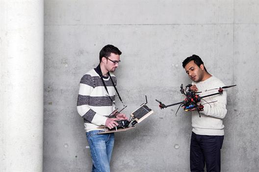 Dieses Bild zeigt zwei männliche Studenten, die an einem Drohnen Projekt arbeiten.